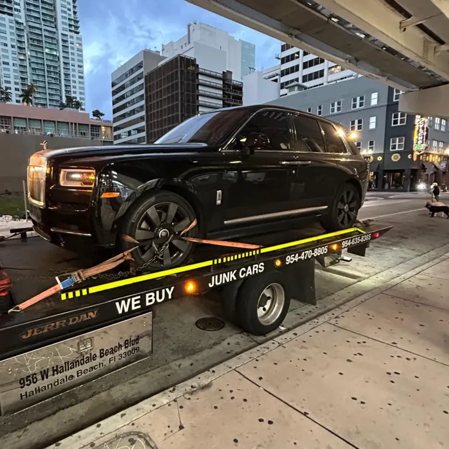 Rolls-Royce Cullinan negro amarrado a la plataforma de Julmar en una calle del downtown de Miami al anochecer