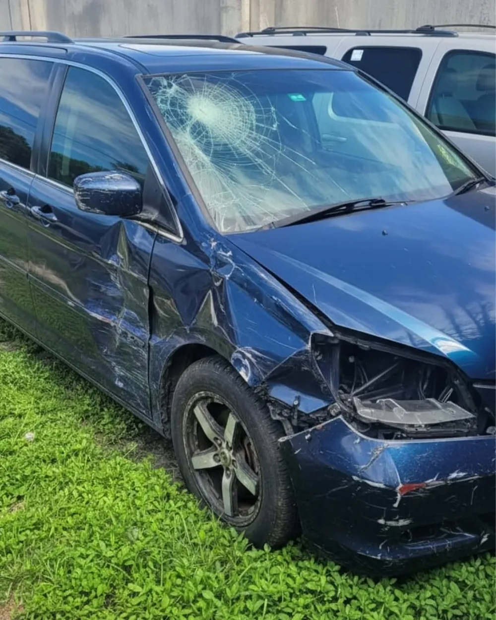 Minivan Honda Odyssey con el parabrisas estrellado y el bumper delantero arrancado